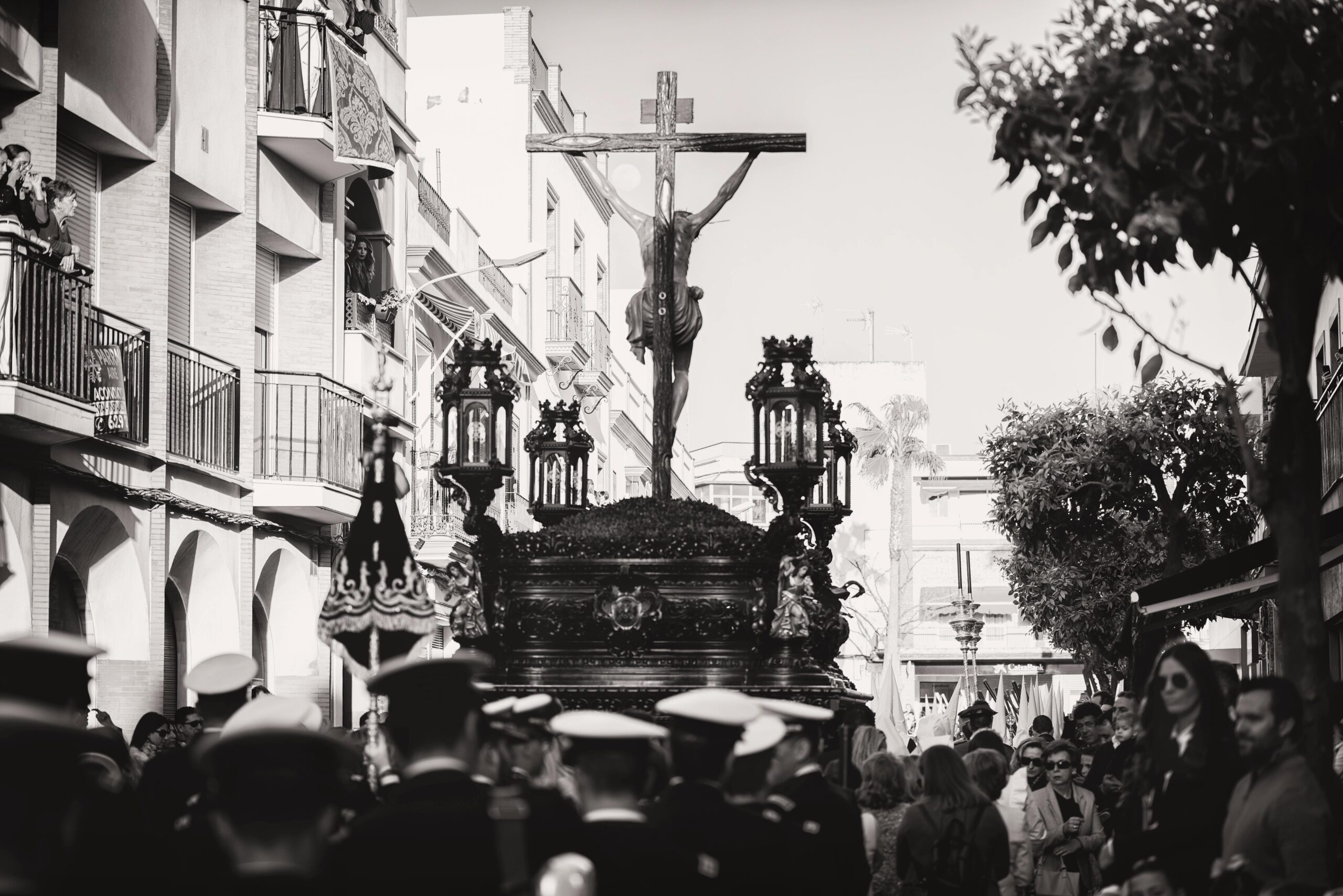Black and white photo of a religious parade in Carmona, Spain featuring a Christ statue and a crowd.